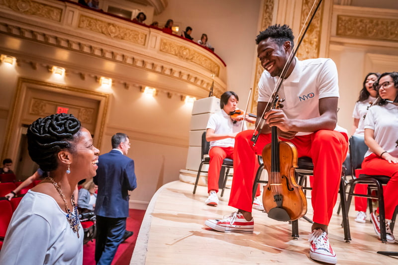 NYO2 student speaking with audience member